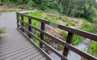 Looking along a pedestrian bridge on to a boardwalk made from recycled plastic