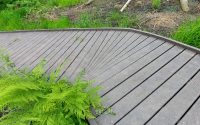 a section of boardwalk with green bracken fronds. the boardwalk is made from recycled plastic to prevent it from rotting