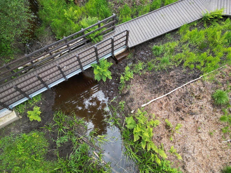 an aerial view of a pedestrian bridge with a boardwalk leading up to the bridge