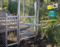 a steel stile and lift up dog gate at the side of a railway