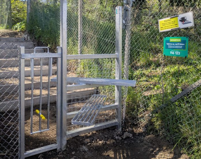 a steel stile and lift up dog gate at the side of a railway
