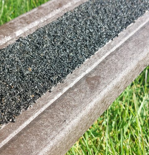 A recycled plastic decking board with tough anti-slip surface